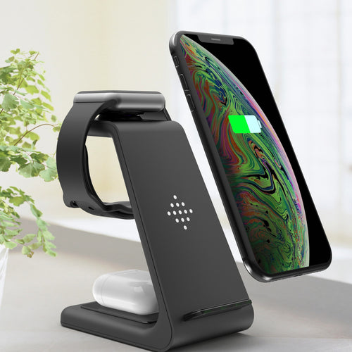 Black wireless charging stand with smartphone, smartwatch, and earbuds on a light background