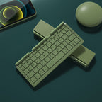 Green keyboard on a dark surface with a phone and mouse in the background